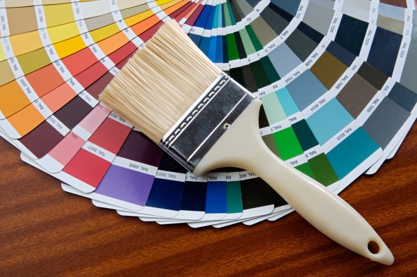 A paintbrush placed on a color palette featuring a wide range of shades, representing the color trends for Dubai homes in 2025
