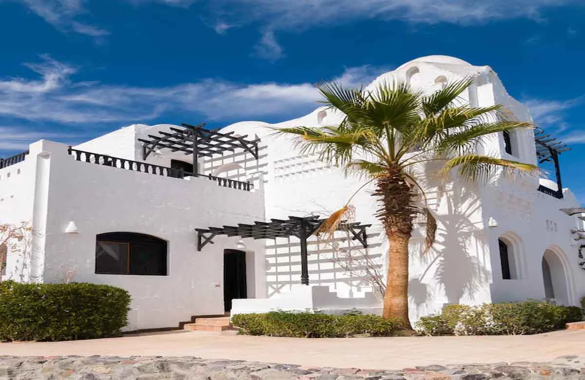 A white-painted villa with modern architecture under a clear blue sky, showcasing premium exterior paint durability in a hot climate.